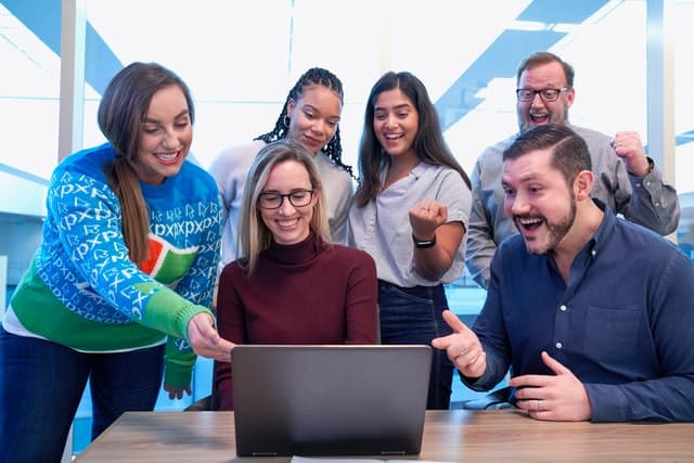 Group of students staring at a laptop