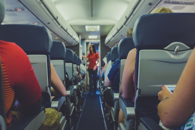Flight attendant standing between passenger seats