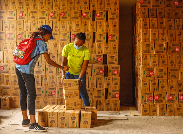 Women standing near carton of boxes