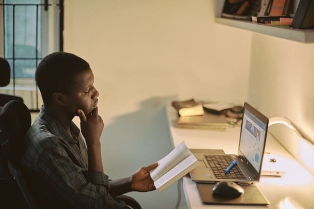 student studying with a laptop and book