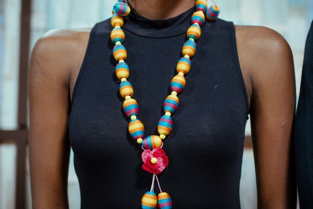 a woman wearing black dress and black and yellow necklace