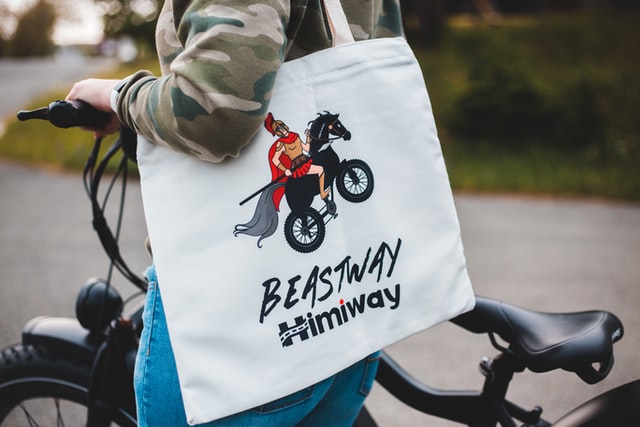 person holding white and black tote bag