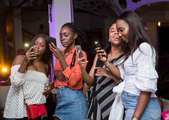 A group of ladies taking pictures with their phones